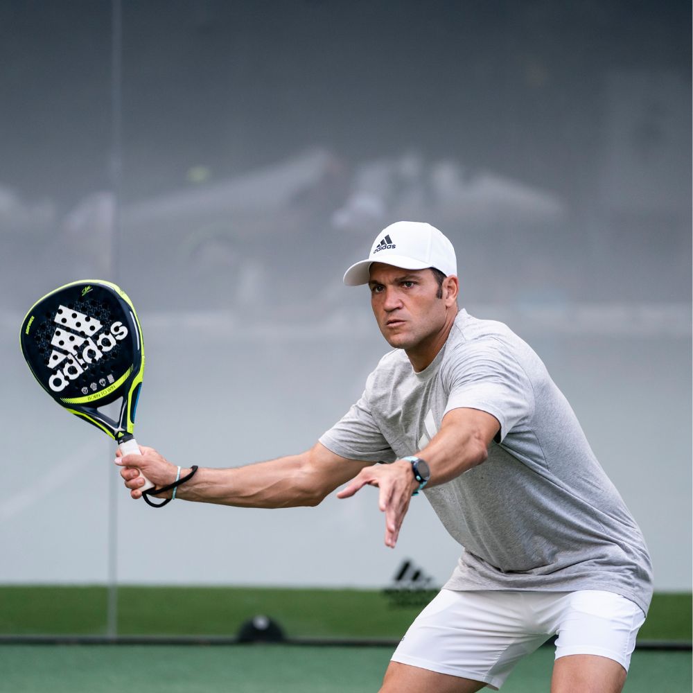 Top Game padel player preparing to serve with Adidas racket on court