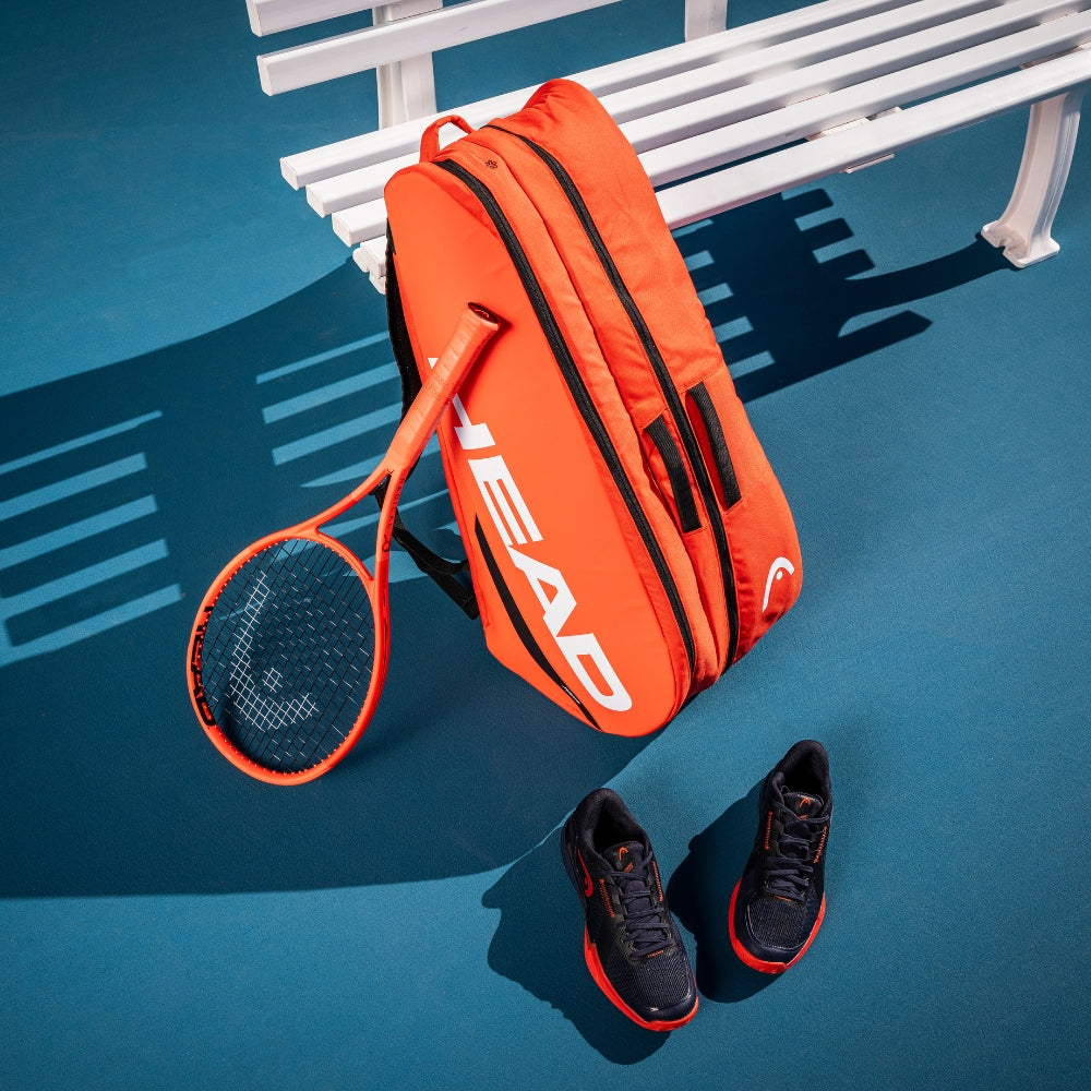 Top Game HEAD tennis bag, racket, and shoes placed beside a white court bench