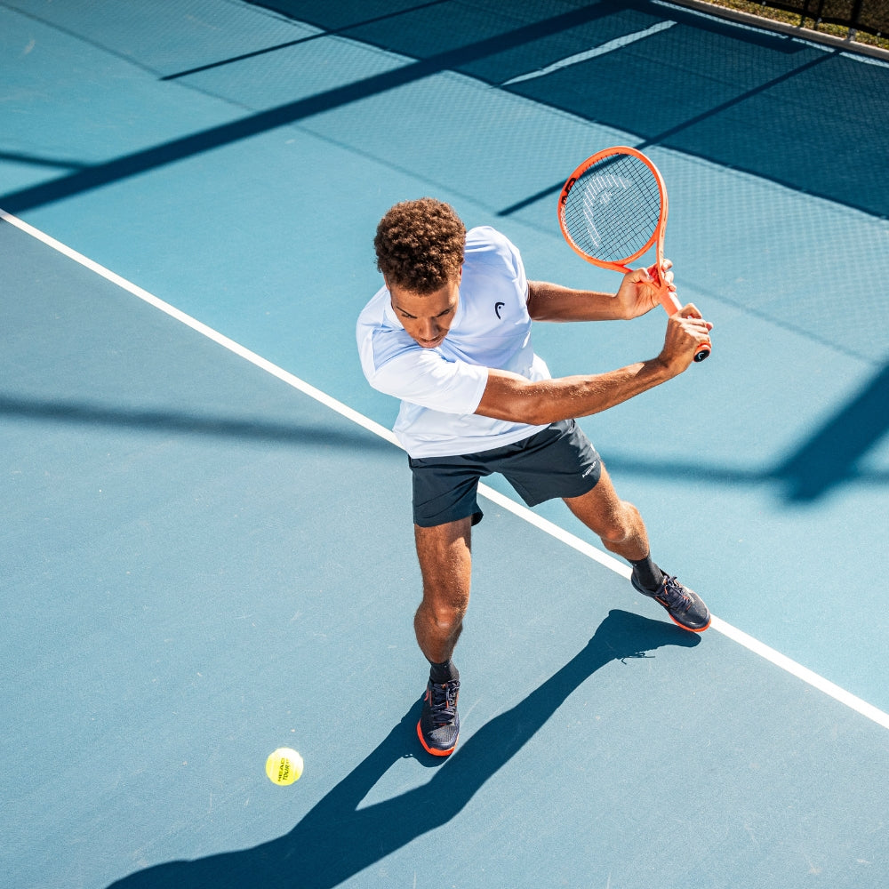 Top Game tennis player hitting a backhand shot on blue hard court