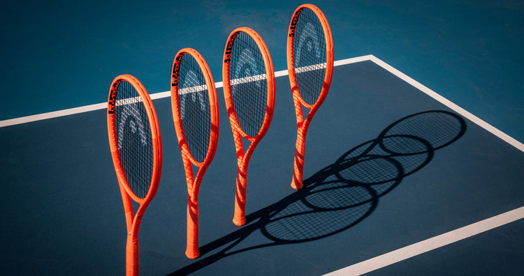 Top Game HEAD tennis rackets with orange frames lined up on blue hard court casting shadows