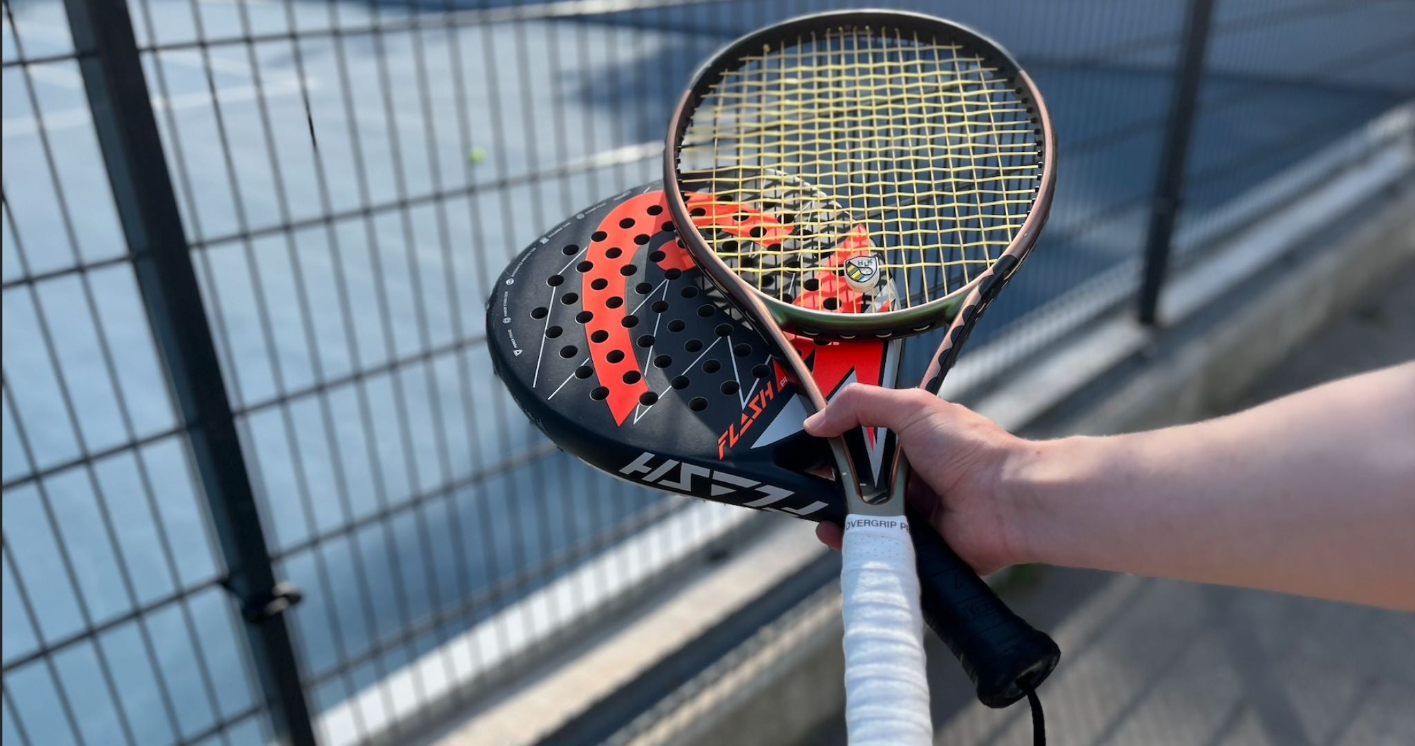Top Game hand holding one tennis racket and one padel racket side by side for comparison