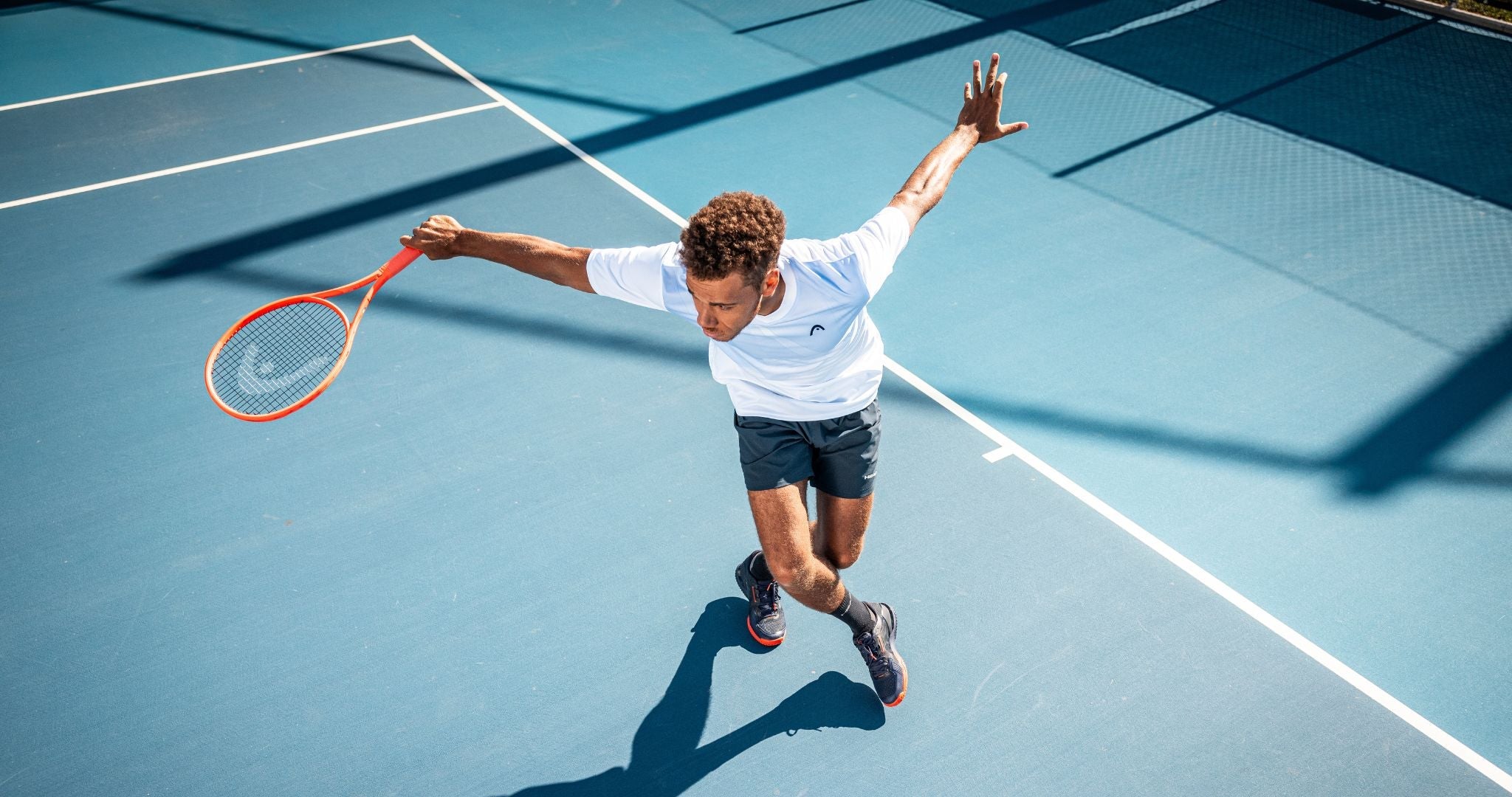 Top Game tennis player celebrating with arms wide open on blue court after point