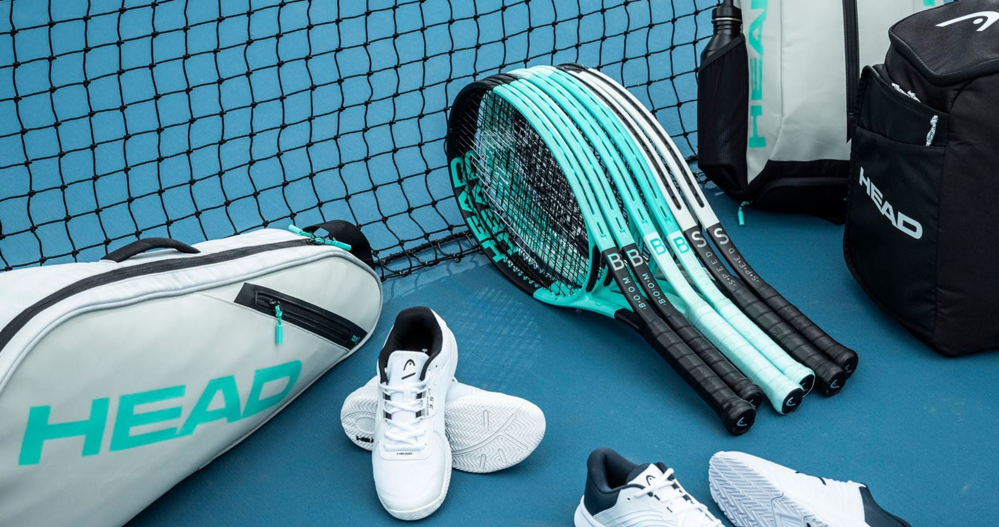Top Game HEAD tennis gear set including rackets, bags, and shoes arranged by net on blue court