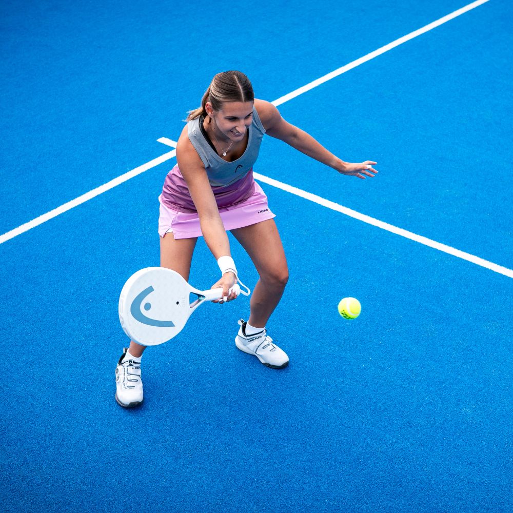 Top Game female padel player in action on vibrant blue court