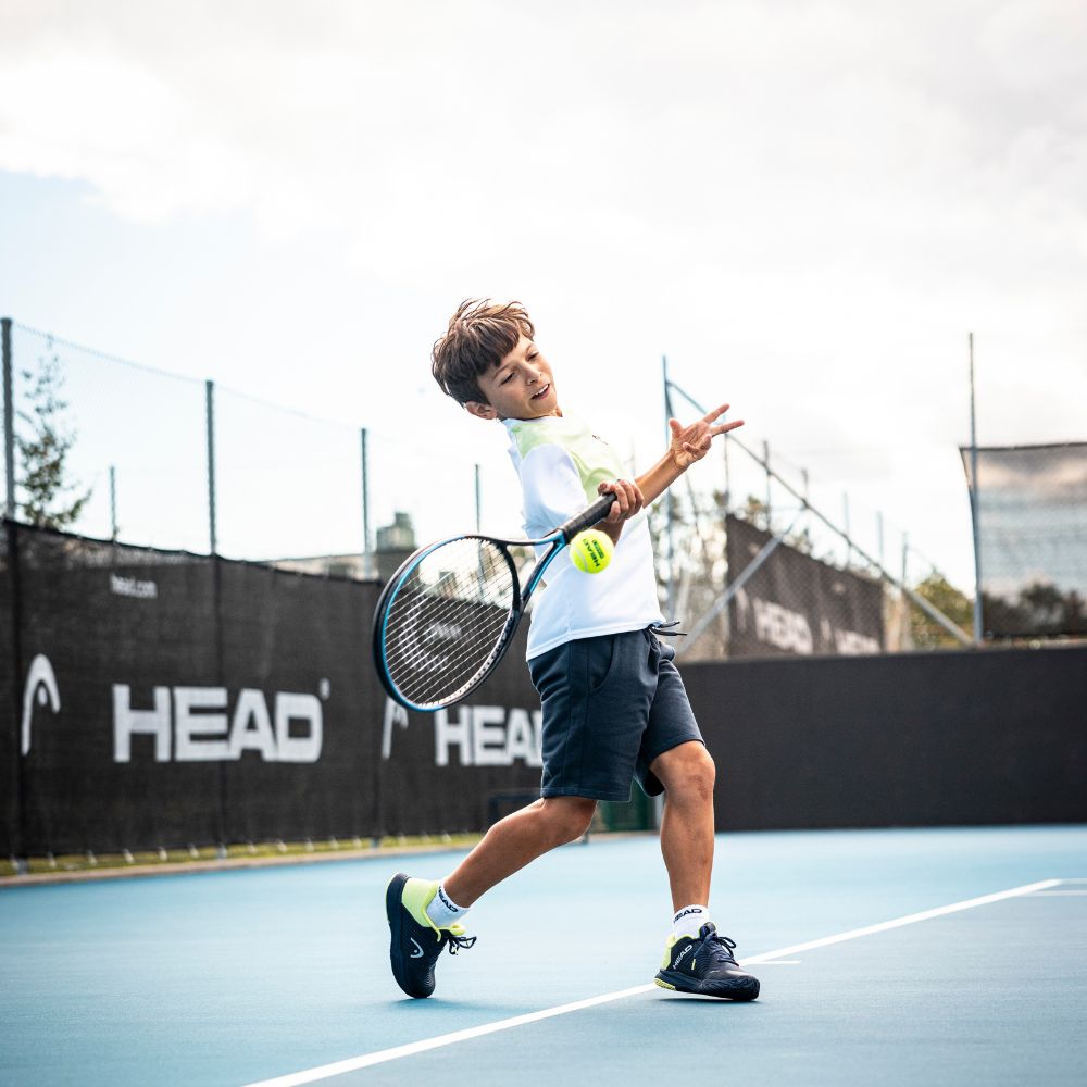 Top Game junior tennis player swinging on HEAD-branded court during training

