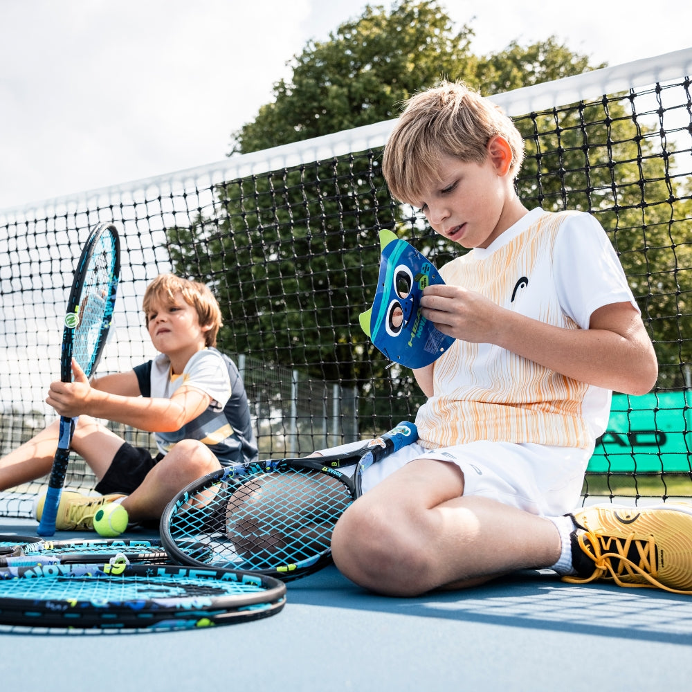 Top Game kids sitting on tennis court with rackets during break time